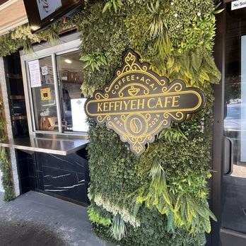 The Keffiyeh Cafe walk-up window set in a wall of green plants